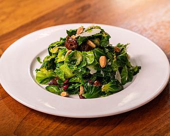 Product: blanched brussels sprouts leaves are tossed with housemade mustard vinaigrette with sliced medjool dates, dried cranberries, toasted almonds, finished with fresh grated manchego cheese - Hub 51 in River North - Chicago, IL American Restaurants