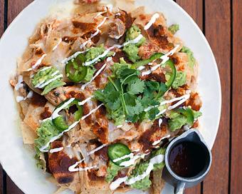 Product: a favorite! housemade tortilla chips are layered with loads of oaxaca and white cheddar cheese and baked until melted. topped with roasted tomato salsa, jalapeño, cilantro, sour cream and pulled chicken - Hub 51 in River North - Chicago, IL American Restaurants