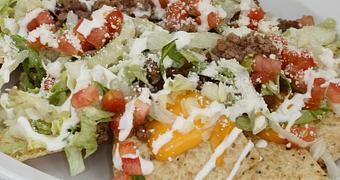 Product: Crispy Nacho chips topped with Sautéed Ground Beef Whole Beans, Onion, Lettuce, Tomato, Melted Cheddar, Cheese & Sour Cream - La Lupita Tacos Mexicanos in Olneyville - Providence, RI Mexican Restaurants