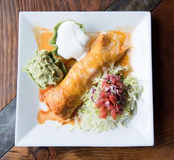 Product: Our most popular burrito! A flour tortilla filled with your choice of chicken or beef. Topped with cheese, onions, tomatoes, lettuce, guacamole and sour cream. Topped with burrito sauce. - Las Brisas Mexican Restaurant in Edmonds, WA Steak House Restaurants