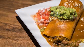 Product: Pork "chile verde," rice, pinto beans, and cheese wrapped in a flour tortilla. Topped with guacamole, tomatoes, onions and enchilada sauce. - Las Brisas Mexican Restaurant in Edmonds, WA Steak House Restaurants
