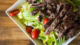 Product: Grass-fed skirt steak on a bed of romaine lettuce mixed with cucumbers, cherry tomatoes, avocado slices, sweet corn and Cotija cheese. Drizzled with a housemade champagne vinaigrette. - Las Brisas Mexican Restaurant in Edmonds, WA Steak House Restaurants