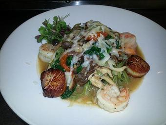 Product: Fresh spinach linguine with seared scallops, sauteed shrimp, wild mushrooms, shaved black truffle, Porcini mushrooms, fresh basil, ice root spinach, oven-dried tomatoes topped with aged Provolone and white truffle oil - Michael Anthony's at the Inn in Versailles, OH Restaurants/Food & Dining