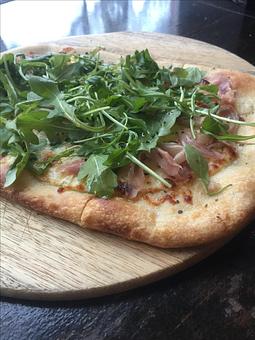 Product: Featuring rich and creamy stracchino cheese, mozzarella and thin slices of prosciutto topped with spicy arugula greens and freshly cracked black pepper. - Paesano Restaurant & Wine Bar in Ann Arbor, MI Italian Restaurants
