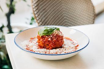 Product: six-ounce prime beef meatball, braised and served in marinara sauce, garnished with grated parmesan, chili flake and fresh basil - Pizzeria Portofino in Chicago, IL Pizza Restaurant
