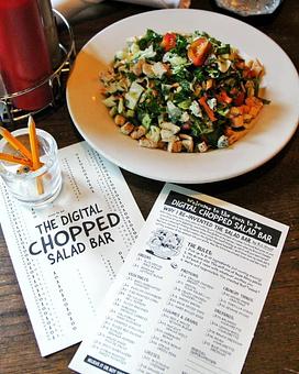 Product: Bowl of salad displayed next to a digital chopped salad menu and a cup of pencils - RJ Grunts in Lincoln Park - Chicago, IL American Restaurants