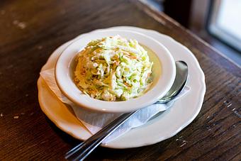 Product: Bowl of RJ Grunts cole slaw served in a white bowl on a white plate with a silver spoon - RJ Grunts in Lincoln Park - Chicago, IL American Restaurants