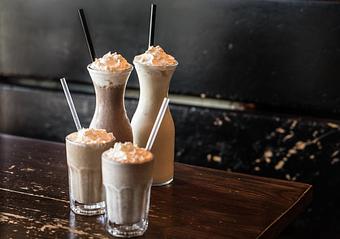 Product: Two chocolate malts served in glasses with two carafes of milkshake behind them - RJ Grunts in Lincoln Park - Chicago, IL American Restaurants