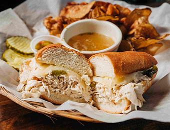 Product: a chicken sandwhich with melted cheese on a baguette with a side of du jour and potato chips - RJ Grunts in Lincoln Park - Chicago, IL American Restaurants