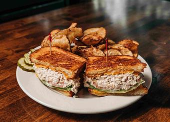Product: a sliced tuna melt on toasted bread with two toothpicks on top of a pile of potato chips - RJ Grunts in Lincoln Park - Chicago, IL American Restaurants