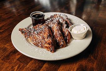 Product: four pieces of thick cut challah bread topped with powdered sugar and served with sides of syrup and whipped butter - RJ Grunts in Lincoln Park - Chicago, IL American Restaurants