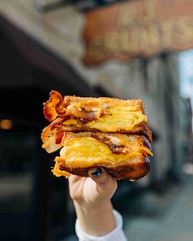 Product: a hand holding two halved bacon egg and cheese sandwiches on thick bread - RJ Grunts in Lincoln Park - Chicago, IL American Restaurants