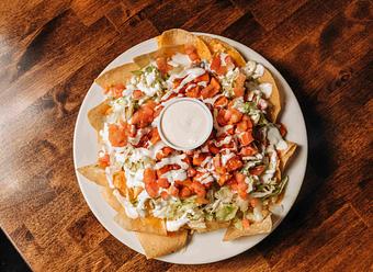 Product: a pile of tortilla chips topped with lettuce, buffalo chicken, tomato, and sour cream - RJ Grunts in Lincoln Park - Chicago, IL American Restaurants