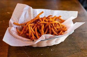 Product: a bowl of thin sweet potato fries in a basket with white parchment paper - RJ Grunts in Lincoln Park - Chicago, IL American Restaurants