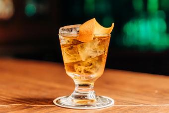 Product: a mini old fashioned in a glass filled with ice and garnished with an orange peel - RJ Grunts in Lincoln Park - Chicago, IL American Restaurants