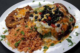 Product: Slow roasted Pork, Chicken, and Short Ribs are stacked in open-faced Enchiladas topped with Colorado Red Sauce, Tomatillo Verde Sauce, Cheddar/Jack cheese, and black bean corn salsa.  Served with your choice of rice and beans. - Shorty's Mexican Roadhouse in Nashua, NH Mexican Restaurants