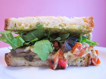 Product: roasted portabella & red pepper, provolone cheese, caramelized onion, arugula & pesto mayo on grilled tuscan bread with a dill pickle - Southport Grocery & Cafe in Lakeview - Chicago, IL American Restaurants