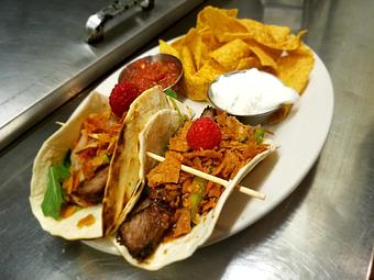 Product: Asian style pear, raspberry, whiskey marinated steak served with grilled tortilla on a bed of baby arugula, steak, raspberry pear taco sauce, pepper, pear slaw, crumbled crunchy wontons and a raspberry for garnish. - The Brass Ring in Madison, WI Bars & Grills