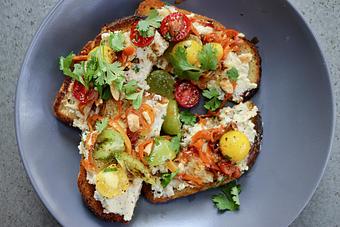 Product: Seasonally inspired menu with daily specials. Pictured: Herbed Ricotta Toast with Summer Pepper Ragout, Cherry Tomatoes, Almonds, Cilantro & Balsamico - The Waterboy in Sacramento, CA American Restaurants