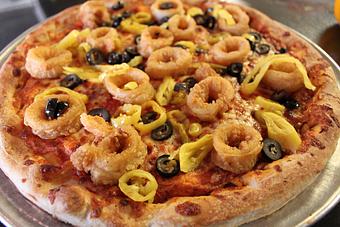 Product: Our traditional cheese pizza topped with fried calamari, fresh garlic, black olives and hot peppers, Available as Large only. 22.25 - Nikolas Pizza in Newport, RI Pizza Restaurant