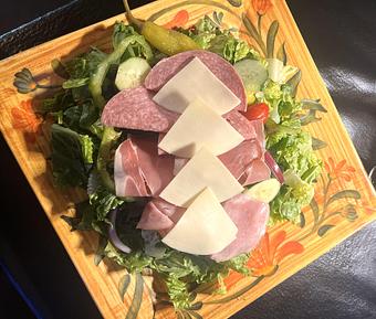 Product: Tomato, cucumber, red onion, green pepper, kalamata olive and pepperoncini over a bed of crisp romaine lettuce. Topped with Genoa salami, ham, prosciutto and Provolone cheese. Dressed in extra virgin olive oil, balsamic vinegar, herbs & spices. - Nikolas Pizza in Newport, RI Pizza Restaurant