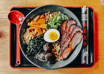 Product: our classic chicken broth with a savory black garlic butter miso, served with tokyo wavy noodles and topped with smoked brisket, braised cremini mushrooms, menma, wakame, molten egg, scallions, fried garlic and rayu - RAMEN-SAN Whisky Bar in Fulton Market - Chicago, IL Japanese Restaurants