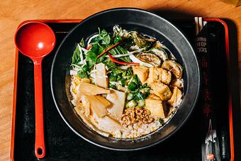 Product: rich coconut broth served with tokyo wavy noodles, lemongrass chili, thai eggplant, fried tofu, shredded cabbage, menma, thai basil, mint, cilantro, makrut lime, green onions and fried garlic. - RAMEN-SAN Whisky Bar in Fulton Market - Chicago, IL Japanese Restaurants
