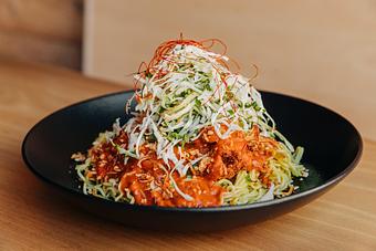 Product: featuring our guest chef, zubair of lilac tiger. This dish uses our tokyo wavy noodles and our popular karaage nuggets sauced with a fragrant spiced tomato sauce, topped with shredded cabbage, green onions, chopped herbs and fried shallot and garlic - RAMEN-SAN Whisky Bar in Fulton Market - Chicago, IL Japanese Restaurants