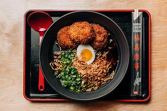 Product: this Filipino inspired ramen features our classic chicken broth, Sun Noodles,  adobo chicken meatballs and topped with scallions, fried garlic and fried shallots - RAMEN-SAN Whisky Bar in Fulton Market - Chicago, IL Japanese Restaurants