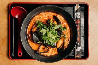 Product: buttery asahi broth served with tokyo wavy noodles, topped with pei mussels, mexican chorizo, herb salad and garnished with fresh ground black pepper and a squeeze of lemon - RAMEN-SAN Whisky Bar in Fulton Market - Chicago, IL Japanese Restaurants