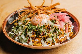 Product: a brothless noodle dish featuring thick temomi noodles, spicy chorizo sauce, onion, cilantro, kosho crema and tortilla strips topped with a poached egg and squeeze of fresh lime juice - RAMEN-SAN Whisky Bar in Fulton Market - Chicago, IL Japanese Restaurants