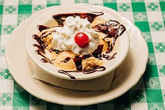Product: A bowl of ice cream with whipped cream, a cherry on top, and chocolate sauce drizzled over the ice cream. - RJ Grunts in Lincoln Park - Chicago, IL American Restaurants