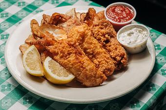 Product: Three pieces of breaded fish served with lemon slices, accompanied by a red sauce and tartar sauce on a white plate atop of a green and white checkered tablecloth - RJ Grunts in Lincoln Park - Chicago, IL American Restaurants