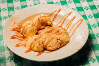 Product: a brown cookie with three scoops of vanilla ice cream and drizzled caramel sauce in a white bowl on a green and white checkered tablecloths - RJ Grunts in Lincoln Park - Chicago, IL American Restaurants