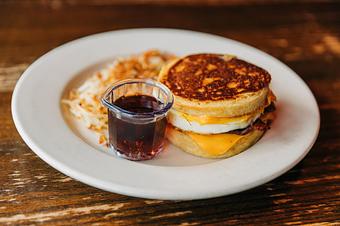 Product: A breakfast sandwich made with pancake buns, served with a side of hash browns and a small side of syrup in a glass - RJ Grunts in Lincoln Park - Chicago, IL American Restaurants