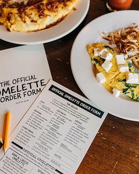 Product: An omelet served on a white plate, placed next to two build-your-own omelet menus and a mini pencil - RJ Grunts in Lincoln Park - Chicago, IL American Restaurants