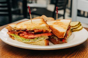 Product: A BLT sandwich with crispy bacon, lettuce, and tomato layered between slices of toasted white bread, served on a white plate - RJ Grunts in Lincoln Park - Chicago, IL American Restaurants