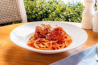 Product: Two large meatballs atop a bed of thick spaghetti noodles in a white bowl - Summer House - Las Vegas in Las Vegas, NV Restaurants/Food & Dining
