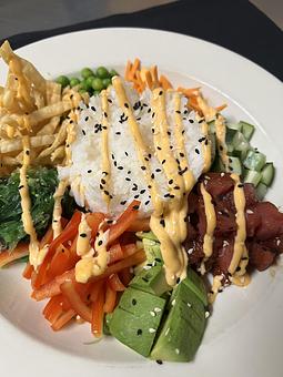 Product: A mound of sticky rice surrounded by seaweed salad, carrots, peas, cucumber, avocado
and fresh tuna drizzled with a sriracha mayo. Served with crispy wontons. - The Bowman in Parkville, MD American Restaurants