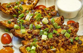 Product: Loaded with crispy bacon & melted cheddar. Topped with green onions and served with Ranch. - The Nugget Bar & Grill in Goleta, CA Bars & Grills