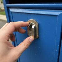 A silver mailbox lock mechanism being installed by Monroe Locksmith Services. Call Us (513) 586-2541